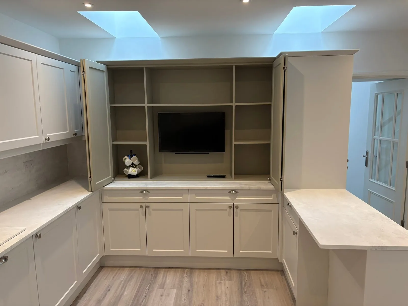 Light fitted media cabinetry with shelving and a built-in desk