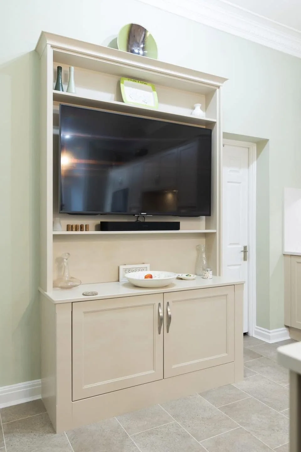 Traditional light-coloured fitted TV cabinet with display shelving
