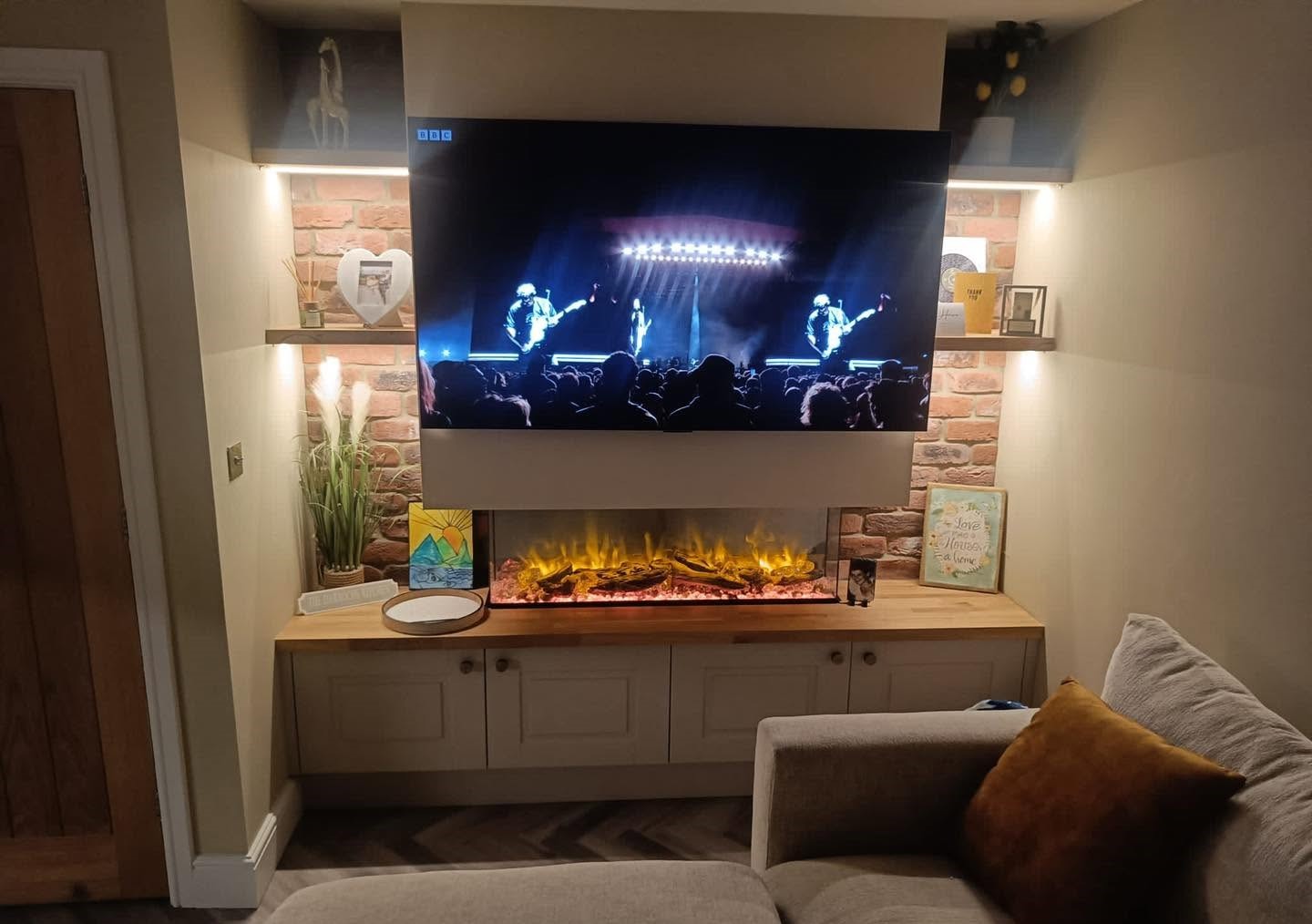 Fireplace media wall with stone-effect tiles and illuminated shelves
